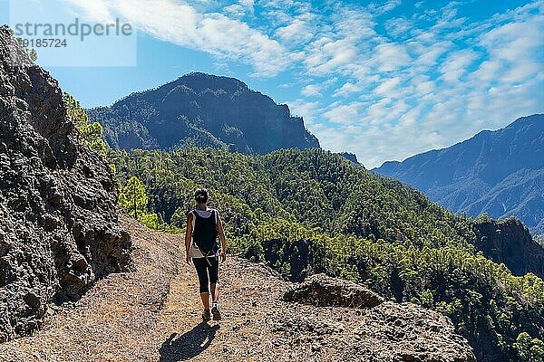 Eine junge Frau ruht sich nach einer Wanderung auf dem Gipfel des La Cumbrecita aus  während sie auf dem natürlichen Aussichtspunkt sitzt und die Berge der Caldera de Taburiente betrachtet  Insel La Palma  Kanarische Inseln  Spanien  Europa