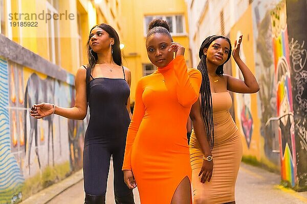 Modischer urbaner Stil mit drei schwarzafrikanischen Mädchen auf einer Stadtstraße  enge Kleider und verführerische Looks. Lifestyle Mädchen der Farbe