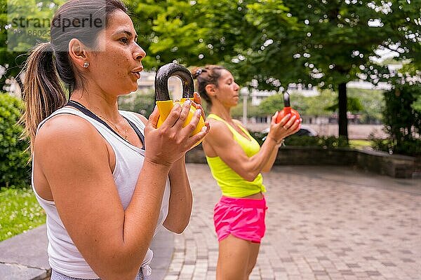 Latin Girl beim Sport in einem Park in der Stadt  Lifestyle ein gesundes Leben  zwei Mädchen beim Training mit Gewichten