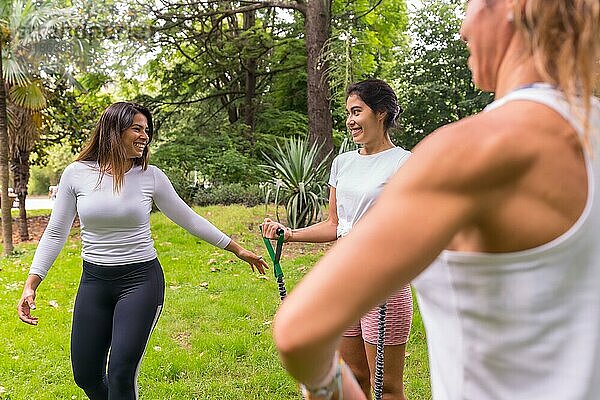 Lateinische Mädchen beim Sport in einem grünen Park  aufmerksamer Konstrukteur mit den Schülern bei der Übung der elastischen Bänder