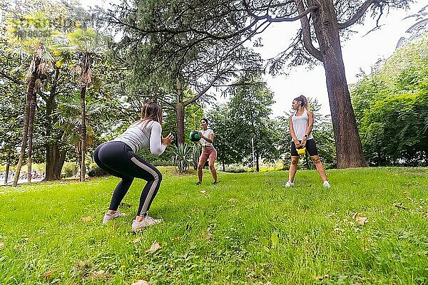 Lateinamerikanisches Mädchen  das in einem grünen Park Sport treibt  Lehrer  der den Schülern eine Reihe von Gewichten beibringt