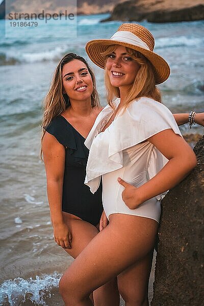 Lebensstil eines lesbischen Paares von kaukasischen Mädchen am Strand im Sommer. Verführerische Blicke der Mädchen schauen in die Kamera