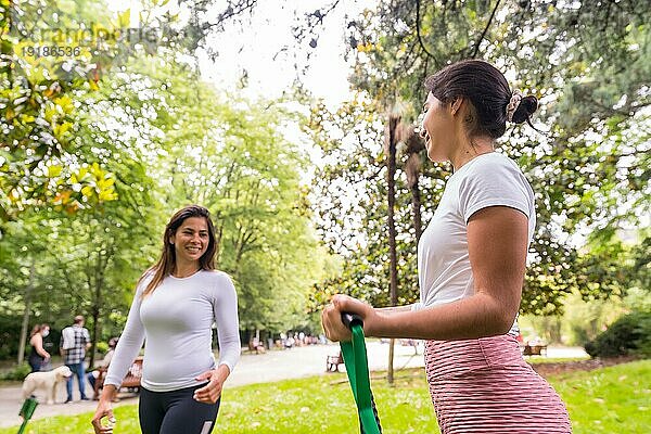 Lateinische Mädchen beim Sport in einem grünen Park  aufmerksamer Konstrukteur mit den Schülern bei der Übung der elastischen Bänder
