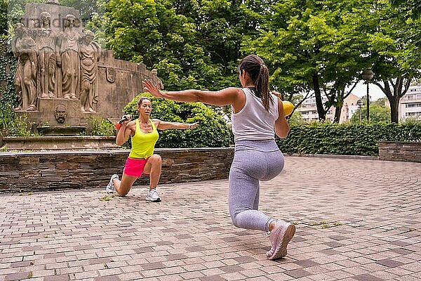 Latin Girl beim Sport in einem Park in der Stadt  Lifestyle ein gesundes Leben  zwei Mädchen tun Stretching Gewichte und Kniebeugen