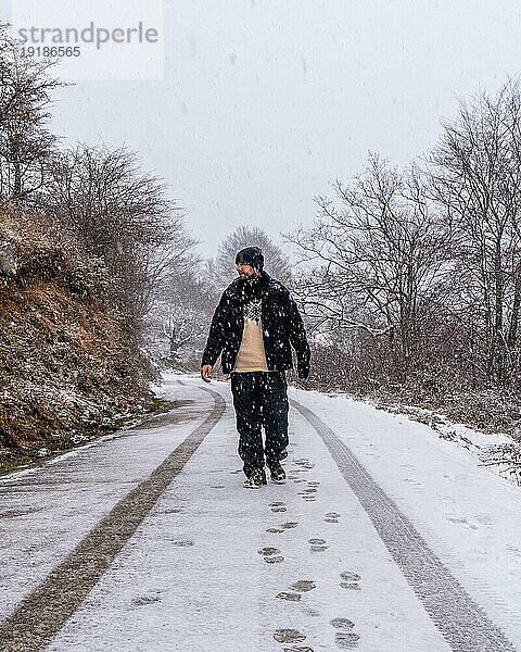 Ein junger Mann vergnügt sich auf der verschneiten Straße des Aizkorri Gebirges in Gipuzkoa. Verschneite Landschaft bei Winterschnee. Baskenland  Spanien  Europa