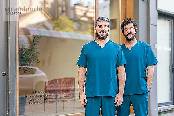 Horizontales Porträt eines fröhlichen medizinischen Teams  das im Eingang einer Klinik steht