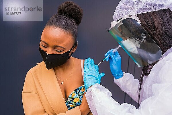 Junges schwarzes Mädchen  das von einem Arzt mit dem Coronavirusimpfstoff geimpft wird  Antikörper  immunisiert die Bevölkerung  gefährdete Personen  neue Normalität  Covid19