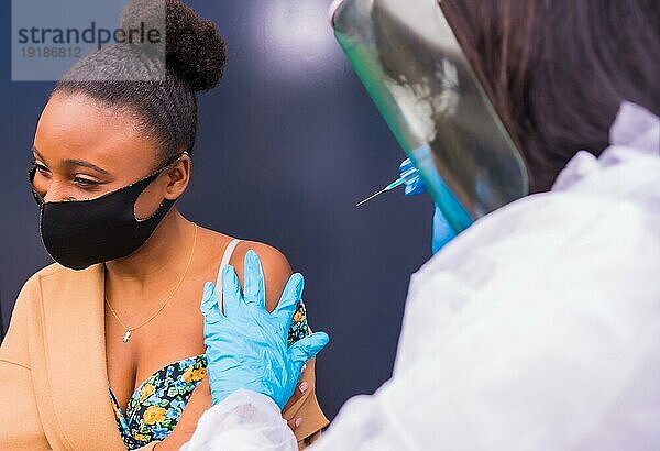 Junges schwarzes Mädchen  das von einem Arzt mit dem Coronavirusimpfstoff geimpft wird  Antikörper  immunisiert die Bevölkerung  gefährdete Personen  neue Normalität  Covid19