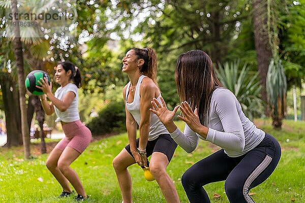 Latino Mädchen beim Sport in einem grünen Park  Lifestyle ein gesundes Leben  Lehrer mit den Schülern tun Kniebeugen mit dem Gewicht Ball