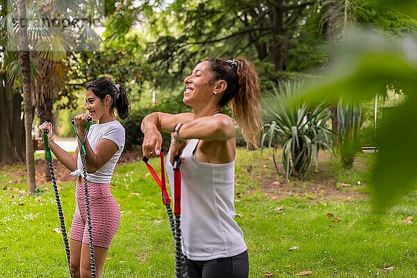 Lateinamerikanisches Mädchen beim Sport in einem grünen Park  gesunder Lebensstil  Studentinnen beim Training mit elastischen Bändern