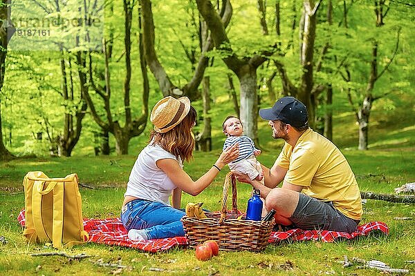 Eine Familie bei einem Picknick mit ihrem neugeborenen Sohn. Bekleidet mit einem weiß gelben TShirt
