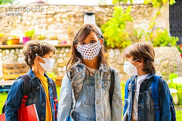Drei Bruderkinder mit Gesichtsmasken  bereit für die Rückkehr in die Schule. Neue Normalität  soziale Distanz  Coronaviruspandemie Covid 19. Mit allen Sicherheitsmaßnahmen