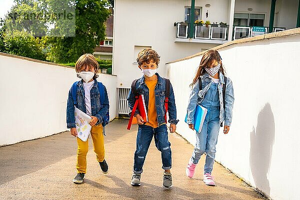 Drei Brüder mit Gesichtsmasken  bereit  wieder zur Schule zu gehen. Neue Normalität  soziale Distanz  Coronaviruspandemie Covid 19. Verlassen des Hauses mit allen Sicherheitsmaßnahmen