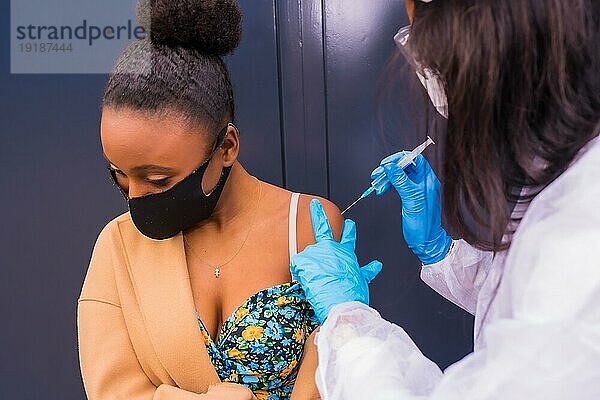 Schwarzes Mädchen  das von einem Arzt mit dem Coronavirusimpfstoff geimpft wird  immunisiert die Bevölkerung  gefährdete Personen  Antikörper  neue Normalität  Covid19