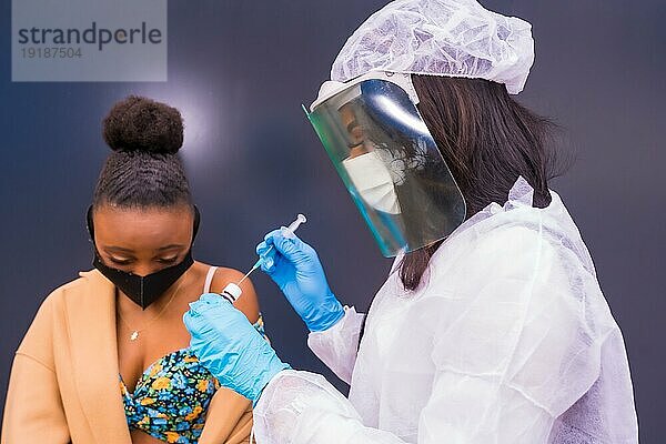 Schwarze Frau  die von einem Arzt eine Impfung gegen das Coronavirus erhält  Antikörper  immunisiert die Bevölkerung  gefährdete Personen  neue Normalität  Covid19