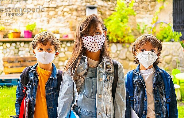 Drei Bruderkinder mit Gesichtsmasken  bereit für die Rückkehr in die Schule. Neue Normalität  soziale Distanz  Coronaviruspandemie Covid 19. Mit allen Sicherheitsmaßnahmen