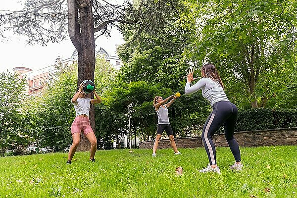 Lateinamerikanisches Mädchen  das in einem grünen Park Sport treibt  Lehrer  der den Schülern eine Reihe von Gewichten beibringt