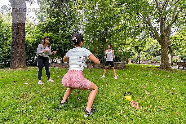 Latina Mädchen bei der Ausübung von Sport in einem grünen Park  aufmerksamer Lehrer im Spiel der Weitergabe der schweren Ball