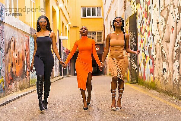 San Sebastián  Gipuzkoa Spanien  Februar 2021: Modischer urbaner Stil mit drei schwarzafrikanischen Mädchen auf einer städtischen Straße. Gehen vorbei und schauen in die Kamera