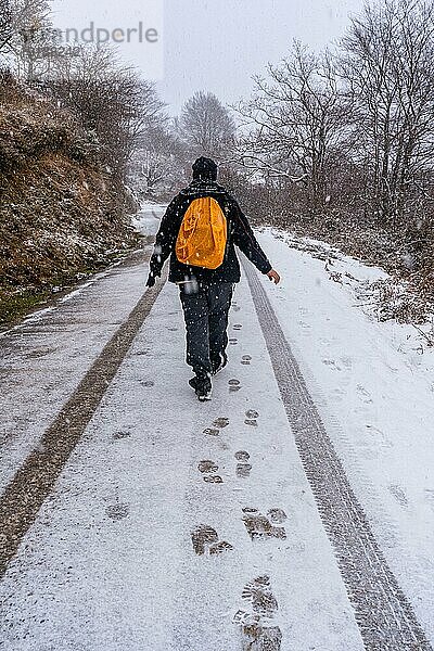 Ein junger Mann vergnügt sich auf der verschneiten Straße des Aizkorri Gebirges in Gipuzkoa. Verschneite Landschaft bei Winterschnee. Baskenland  Spanien  Europa