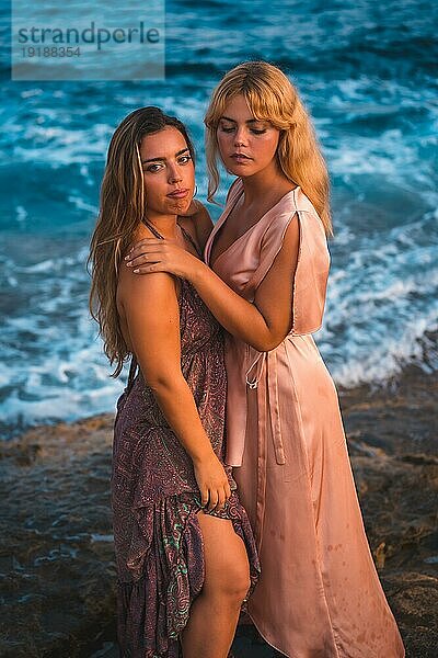 Ein paar kaukasische Mädchen in rosa Kleidern  posieren Sommer am Strand am Meer  Foto von oben