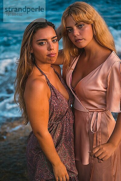 Ein paar kaukasische Mädchen in rosa Kleidern  posieren Sommer am Strand am Meer  Foto von oben