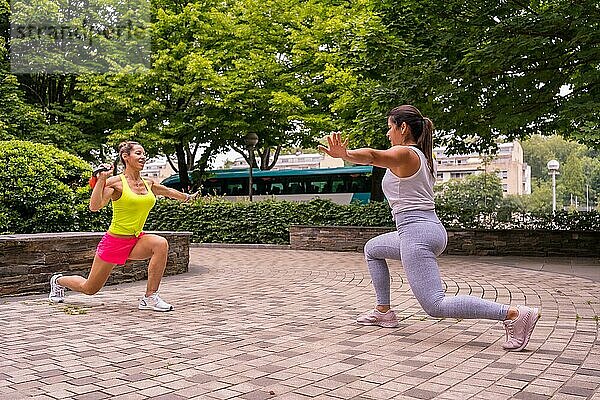 Latin Girl beim Sport in einem Park in der Stadt  Lifestyle ein gesundes Leben  zwei Mädchen tun Stretching Gewichte und Kniebeugen