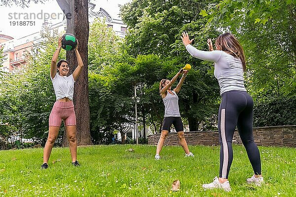 Lateinamerikanisches Mädchen  das in einem grünen Park Sport treibt  Lehrer  der den weiblichen Schülern Übungen mit Gewichten beibringt