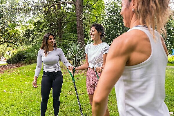 Lateinische Mädchen beim Sport in einem grünen Park  aufmerksamer Konstrukteur mit den Schülern bei der Übung der elastischen Bänder