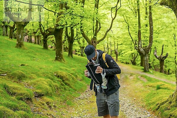 Ein junger Vater mit einem gelben Rucksack zu Fuß mit dem neugeborenen Kind in den Rucksack auf einem Weg in den Wald auf dem Weg zum Picknick mit der Familie