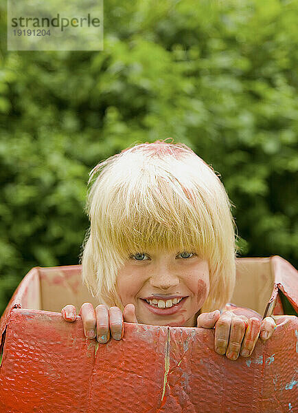 Nahaufnahme eines jungen blonden Jungen lächelnd in einem Karton