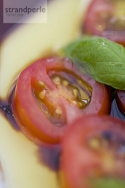 Kirschtomaten und Basilikumblätter in Olivenöl-Balsamico-Dressing