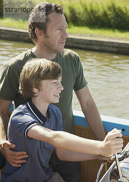 Mann und lächelnder Teenager steuern ein Boot