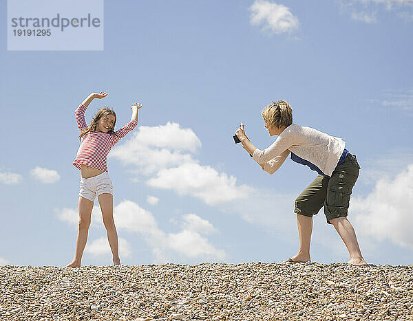 Frau fotografiert ein junges Mädchen am Strand