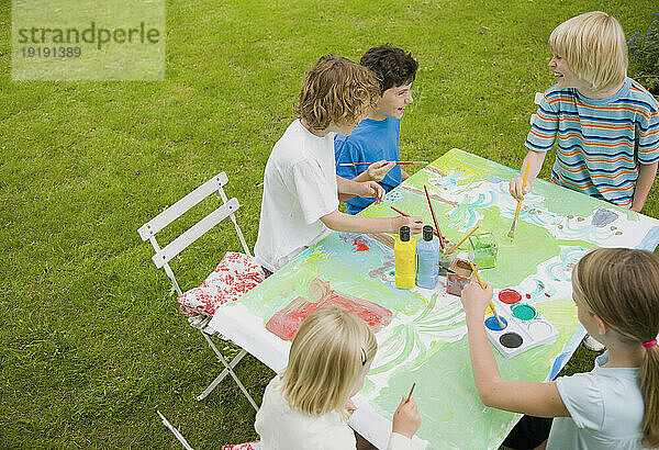 Kinder sitzen und malen im Garten