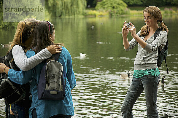 Teenagermädchen fotografiert zwei Frauen an einem See
