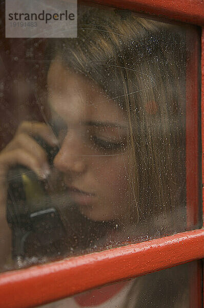 Teenager-Mädchen telefoniert in einer Londoner Telefonzelle