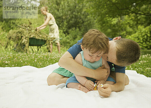 Kleiner Junge sitzt in einem Garten und umarmt und küsst seinen kleinen Bruder