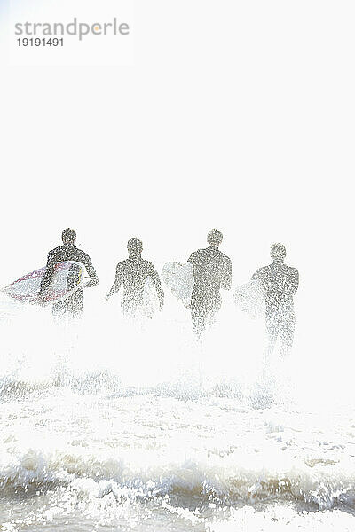 Rückansicht von Surfern  die mit Surfbrettern im Meer laufen