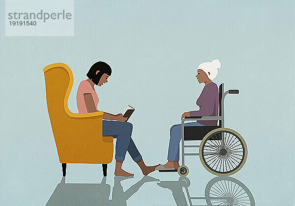 Frau im Sessel liest einer älteren Frau im Rollstuhl ein Buch vor