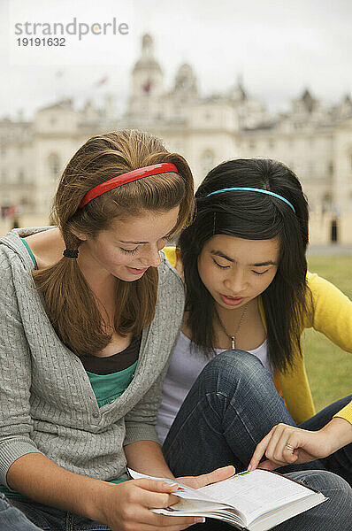 Zwei Teenager-Mädchen lesen ein Buch vor der London Horse Guards Parade