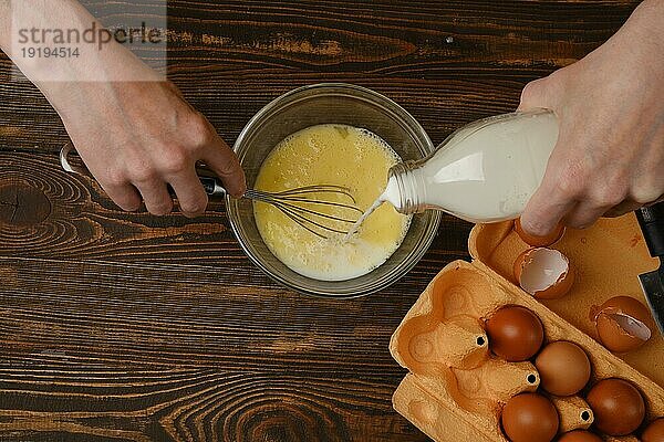 Draufsicht auf das Gießen von Milch in Eier. Zubereitung eines Omeletts