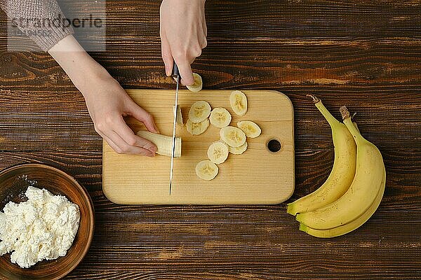 Unbekannte Person schneidet Bananenscheiben  Draufsicht