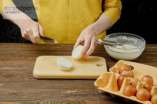 Unbekannter Mann mittleren Alters schneidet Zwiebelknolle in zwei Hälften