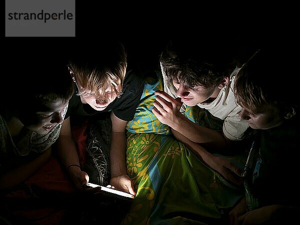 Jungs liegen nachts im Bett zusammen und schauen in ihr Handy  Deutschland  Europa