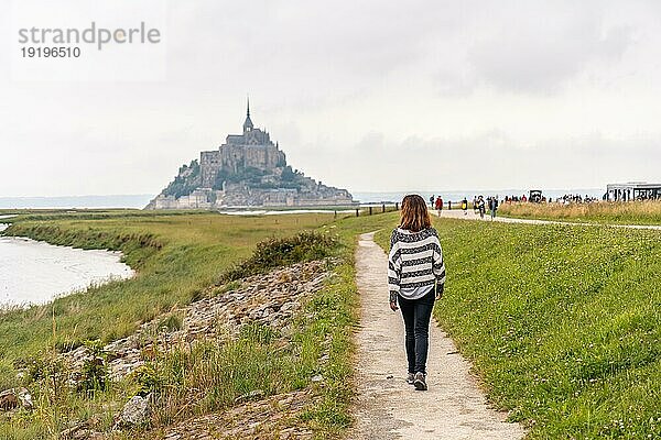 Ein junger Tourist geht vom Point de Vue in Richtung der Abtei Mont Saint Michel  Region Normandie  Frankreich  Europa