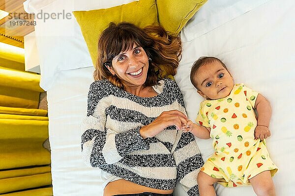 Porträt einer jungen Mutter mit ihrem Baby  die sich in ihrem Bett im Schlafzimmer vergnügt  kaukasische Erstgebärende mit ihrem vier Monate alten Baby  Familie zu Hause