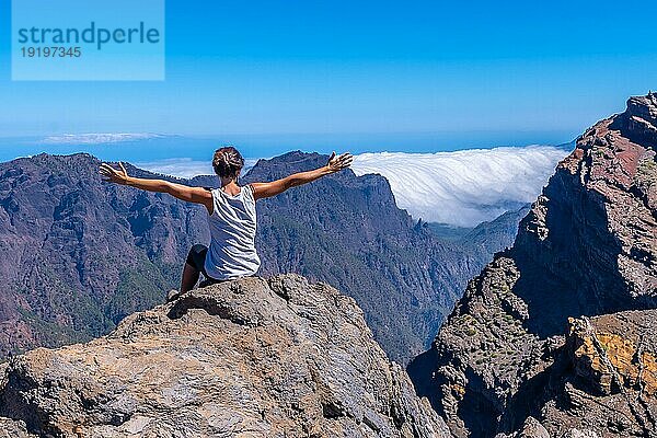 Eine junge Frau ruht sich aus und genießt die Aussicht auf den Nationalpark Roque de los Muchachos auf dem Gipfel der Caldera de Taburiente  La Palma  Kanarische Inseln. Spanien