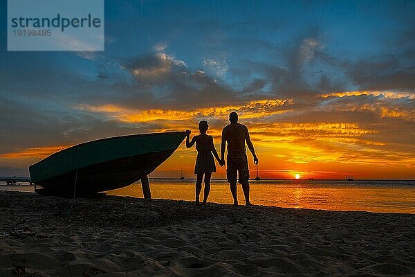 Ein verliebtes Paar bei Sonnenuntergang auf Roatan von West End aus. Honduras