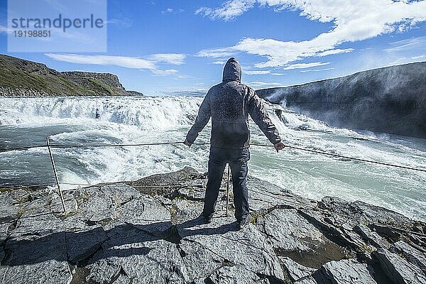 Ein junger Mann über dem Gullfosswasserfall im Goldenen Kreis im Süden von Island